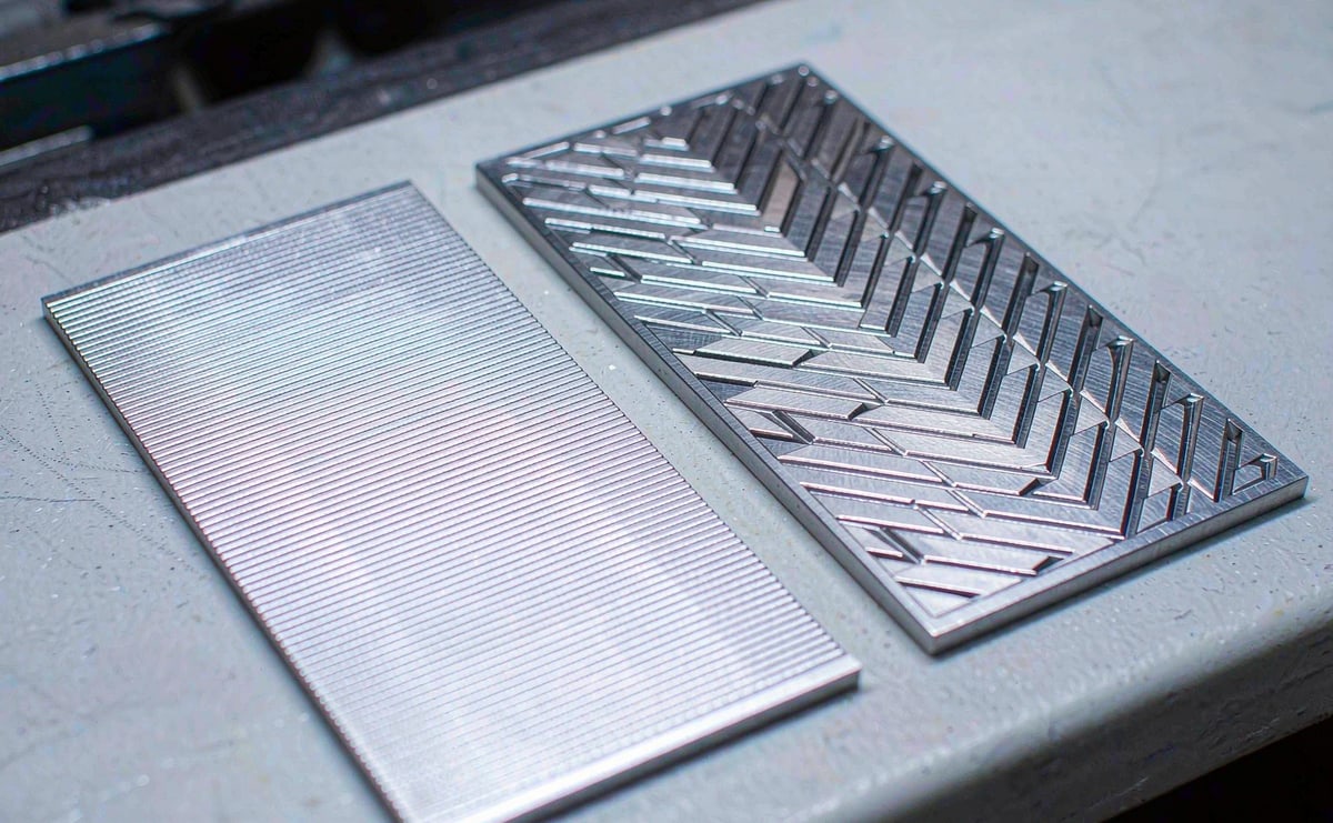 Two thin metal plates side by side, one with a fine graduated pattern and one with an abstract cut pattern
