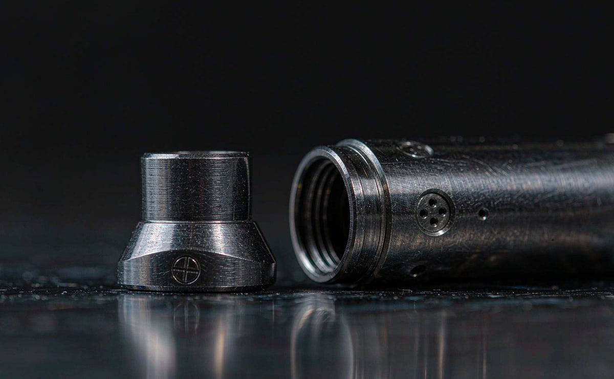 Metal cap and barrel separated and aligned, the clearance between mating surfaces clearly visible