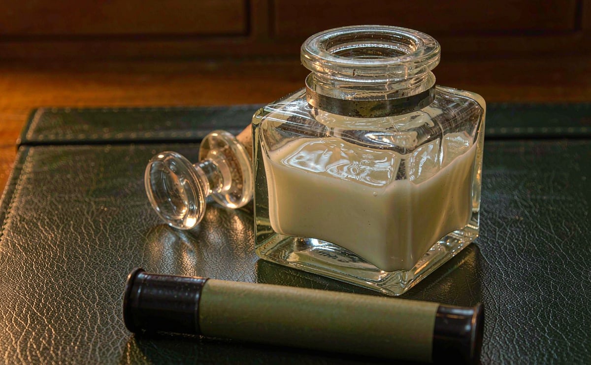 Glass ink bottle beside a sealed ink cartridge