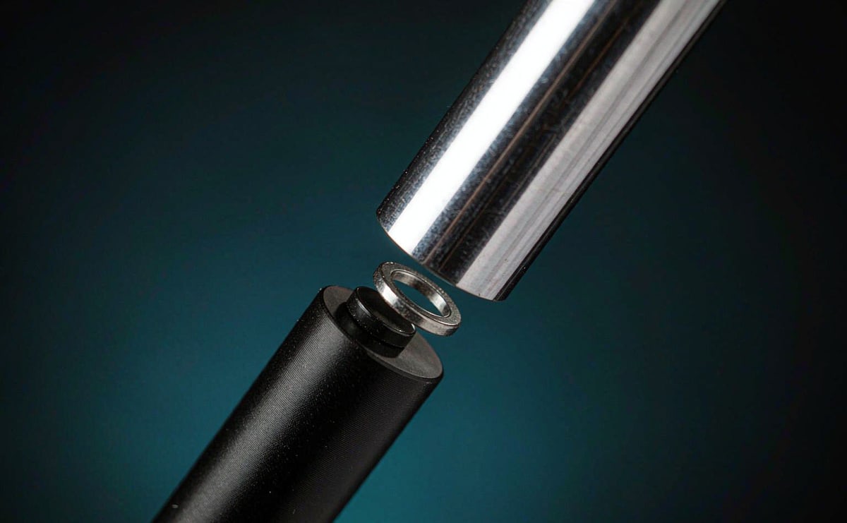 Two small round magnets drawing a metal cap toward a barrel, the cap slightly lifted to reveal the joint