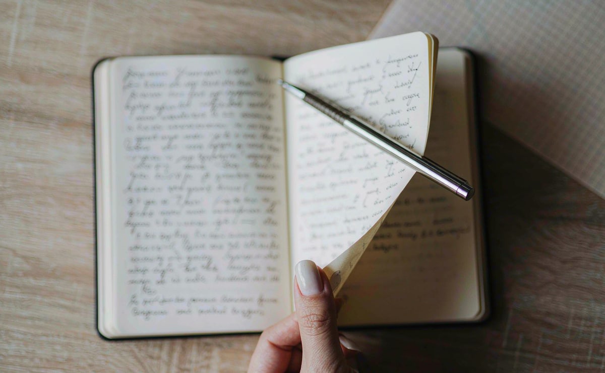 A metal pen being used in a notebook